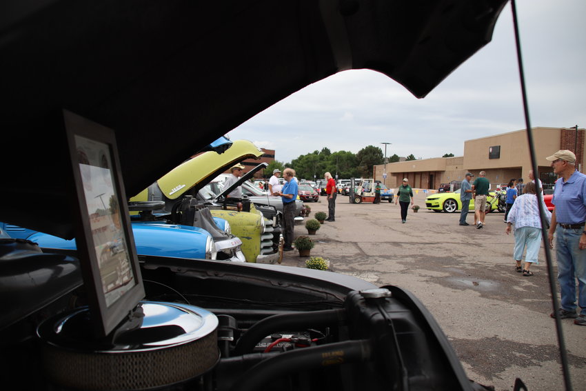 Community members inspect an array of classical cars, some nearly a century old.